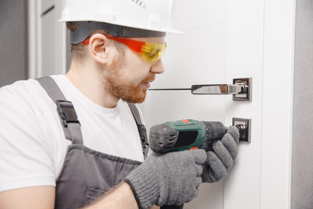 Male carpenter wood door installation working tightens lock