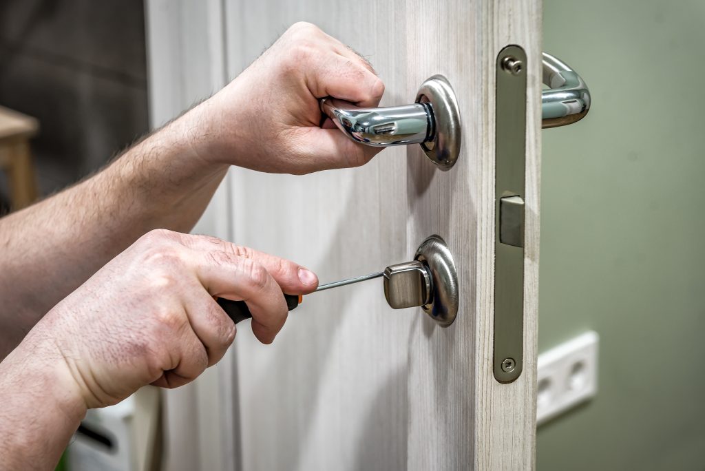 Professional handyman repair the door lock in the room, locksmith fixing lock with screwdriver