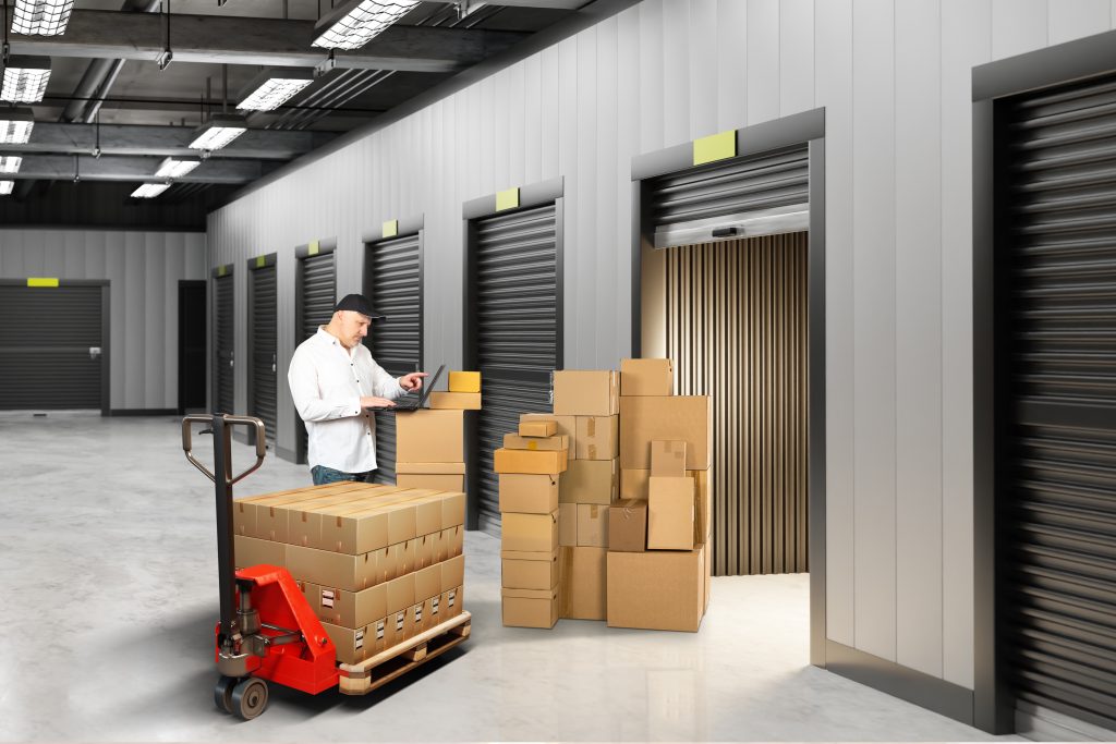 Storage auction. Man near warehouse unit. Boxes at entrance to storage container. Businessman bought warehouse unit at auction. Male in hallway of storage company. Guy is in warehouse business.